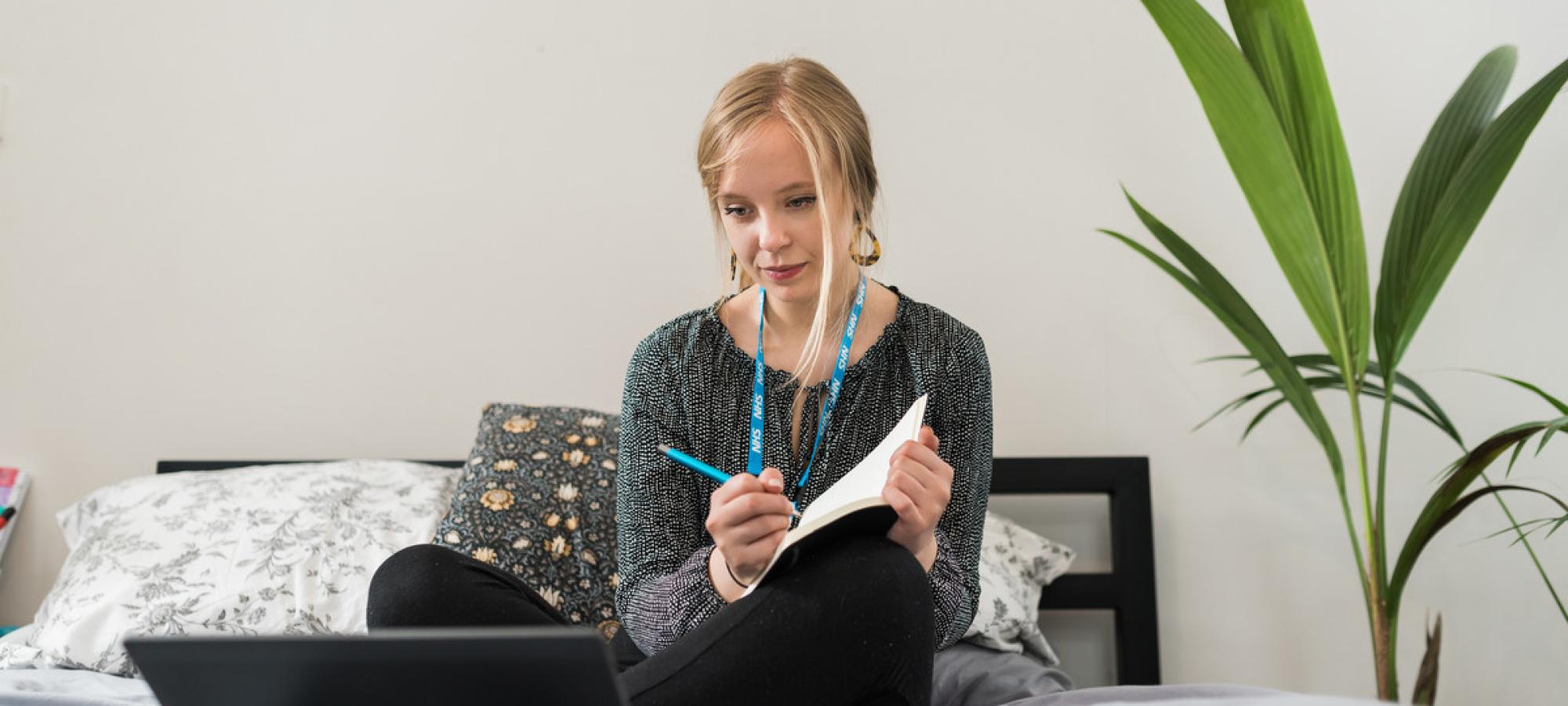 Grace, Change 100 intern, writing in her notepad while working from home