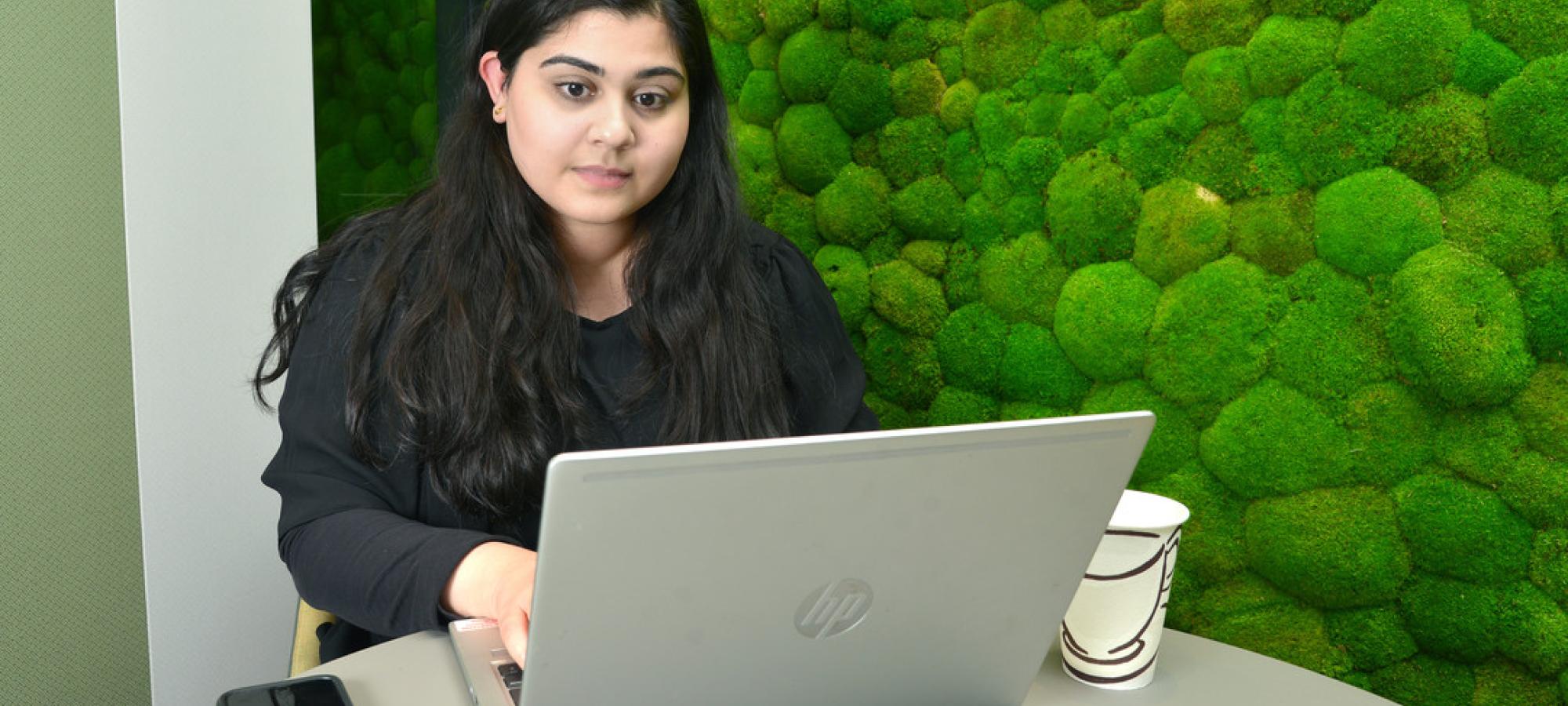 Sakina using her laptop during her internship at Overbury