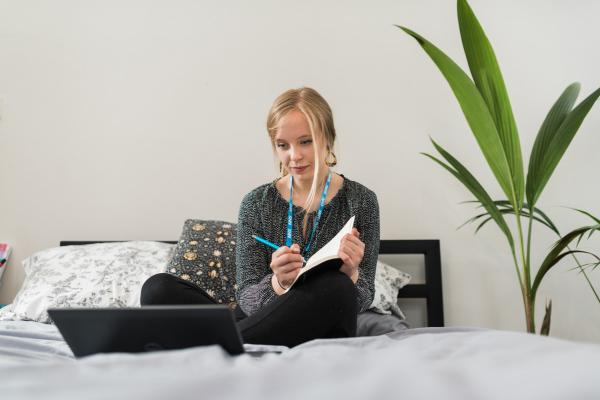 Grace, Change 100 intern, writing in her notepad while working from home