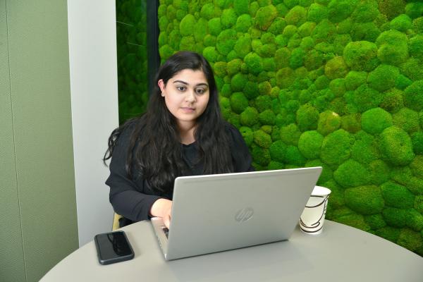Sakina using her laptop during her internship at Overbury