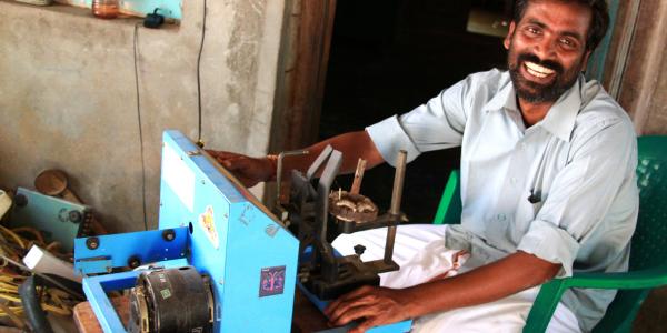 A man smiling at the camera in front of a machine