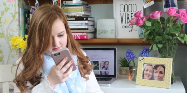 Emily Davison holding her phone in her bedroom