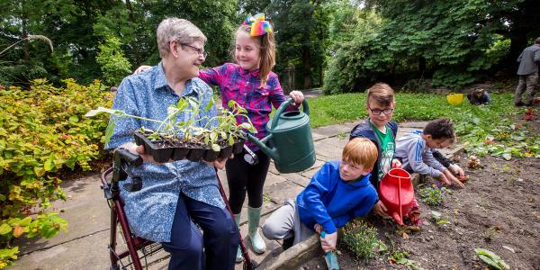 A young girl helps an older woman in the garden