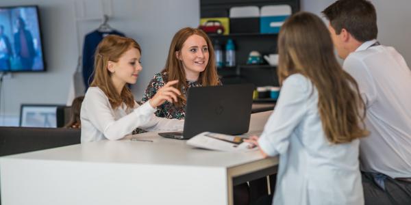 A group of Change 100 interns sitting around a table in an office.