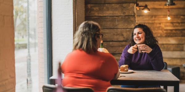 Two friends sat at a table drinking coffee at the Social Bean coffee shop