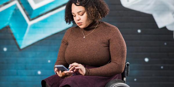 Cassie in her wheelchair looking at her phone