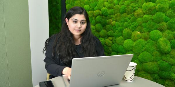 Sakina using her laptop during her internship at Overbury