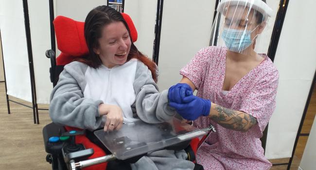 Carer in a PPE with a resident laughing