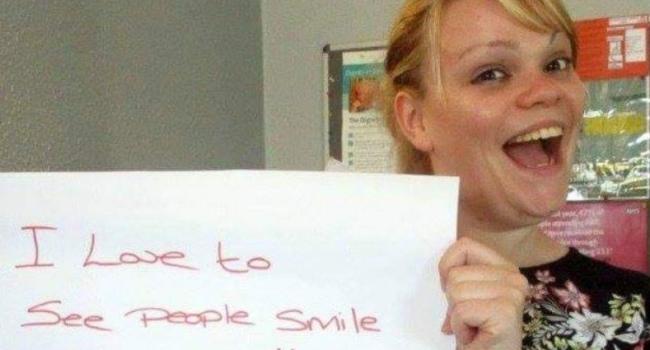 Steph holding at a sign that says "I love to see people smile"