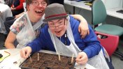 A woman and man sitting next to each other with a tray of soil in front of them
