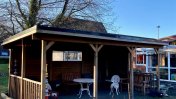 Chipstead garden exterior with a wooden shelter with white table and chairs 