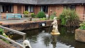 Building surrounding a pond with a water feature and Pelican statues