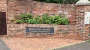 Front gate of building with a Newlands House sign on the red brick wall outside