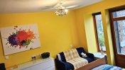 A yellow painted bedroom with wall art on the wall a white chest of drawers and a single bed