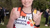 A dark haired caucasian woman with plaits wearing a Leonard Cheshire branded vest with the name 'Emily' across it 