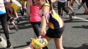 A Caucasian dark haired runner wearing a branded vest leaning over to grab a supporters hand