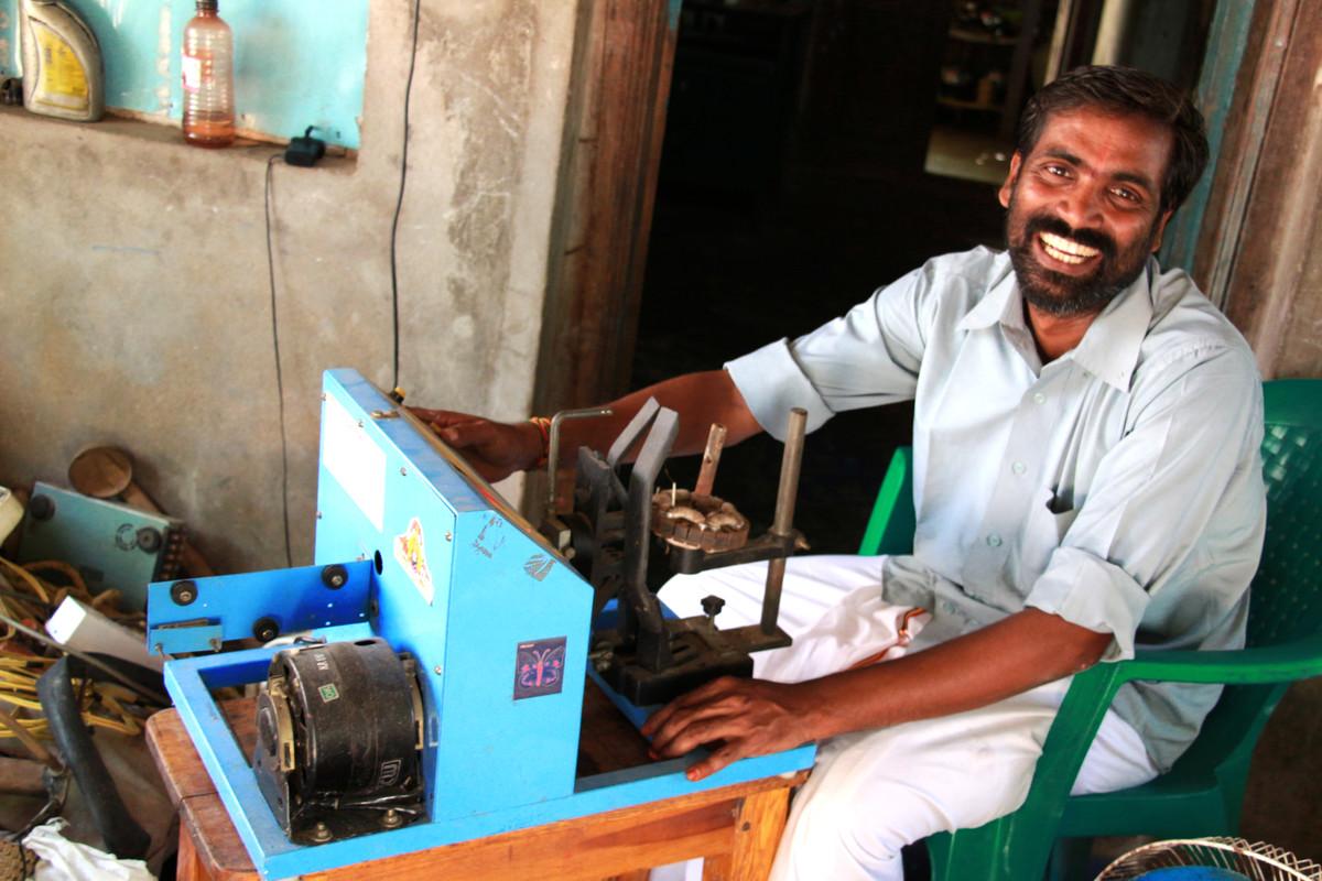 A man smiling at the camera in front of a machine