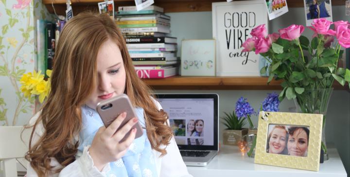 Emily Davison holding her phone in her bedroom