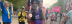 An asian male with a grey beard and black turban wearing a Leonard Cheshire branded vest holding up his running medal in front of other scattered marathon runners