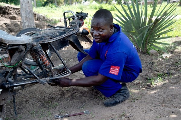 Itra Daniel is a mechanic, knelling in from of a bike