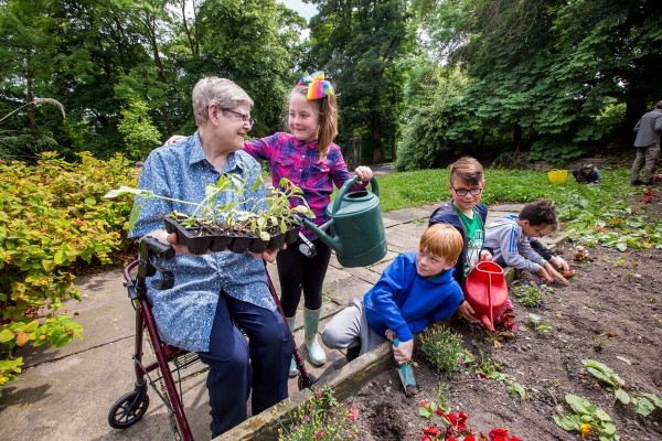 A young girl helps an older woman in the garden