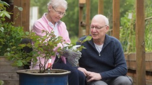 Two people, a man and a woman, plant a rose in memory of Kay
