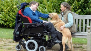 Tom in his wheelchair with his mum and a guide dog