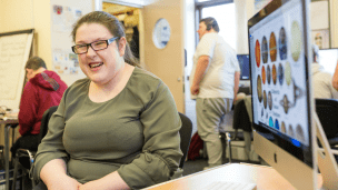 Woman next to a computer screen laughing