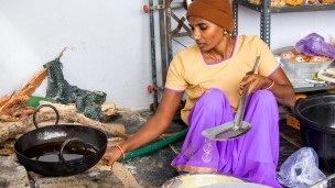Woman sitting on the floor next to a pan cooking