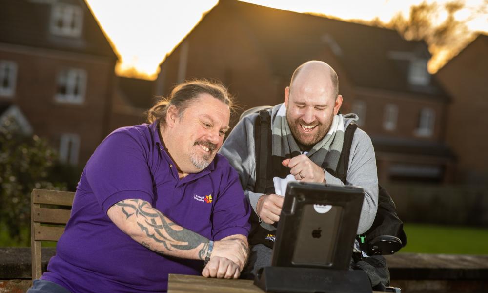 To men look at a computer screen and laugh