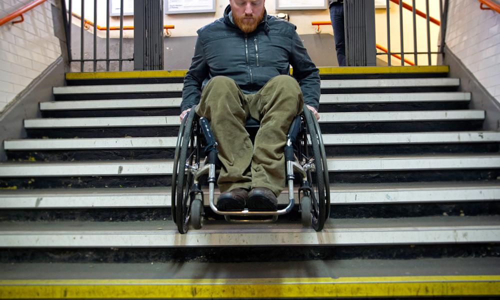 Male wheelchair user going down the stairs in his wheelchair at a train station