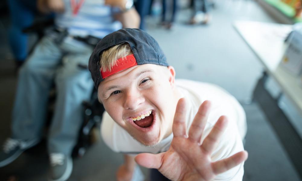A boy wearing a hat reaching his hand up to the camera