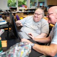 Orchard resident Declan with Brian a volunteer in front of a computer