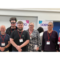 The AT team stood together smiling in front of conference boards 