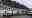 The back of building with  garden planters and a white Minibus parked outside 
