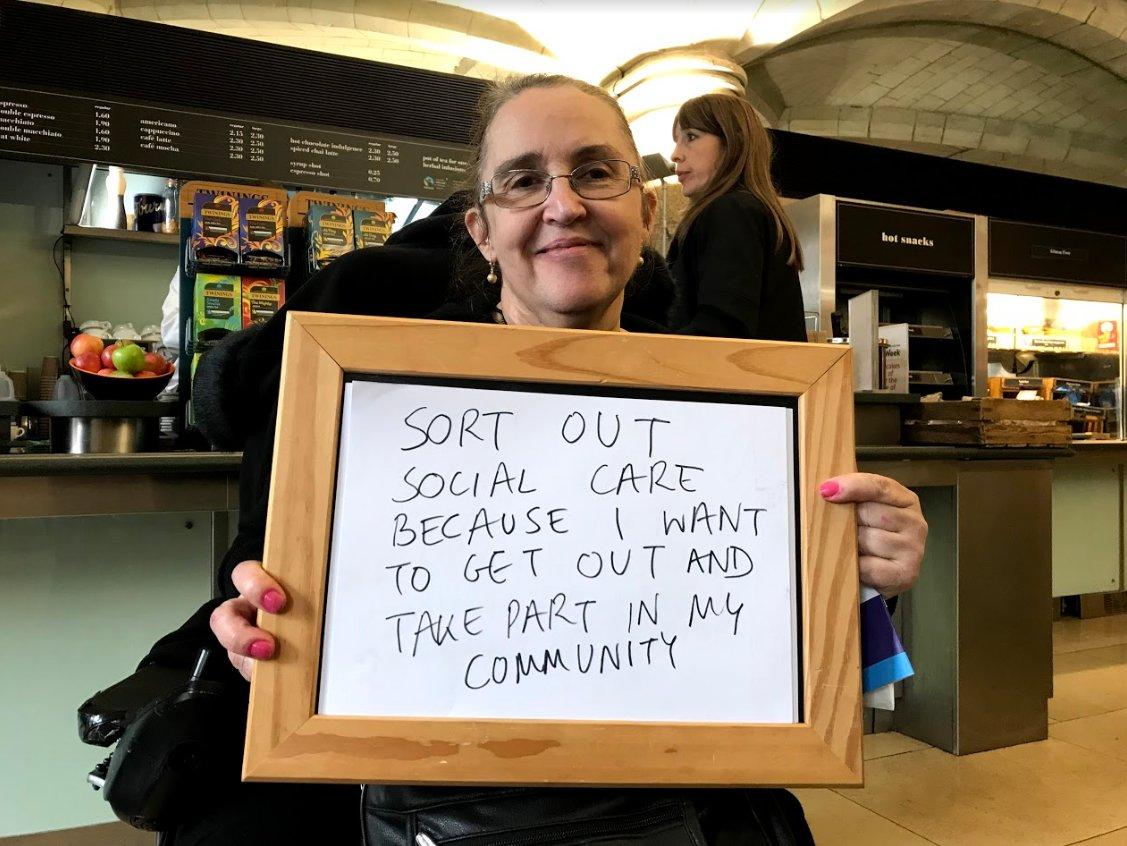 A campaigner holds a sign that reads 'Sort out social care because I want to get out and take part in my community'