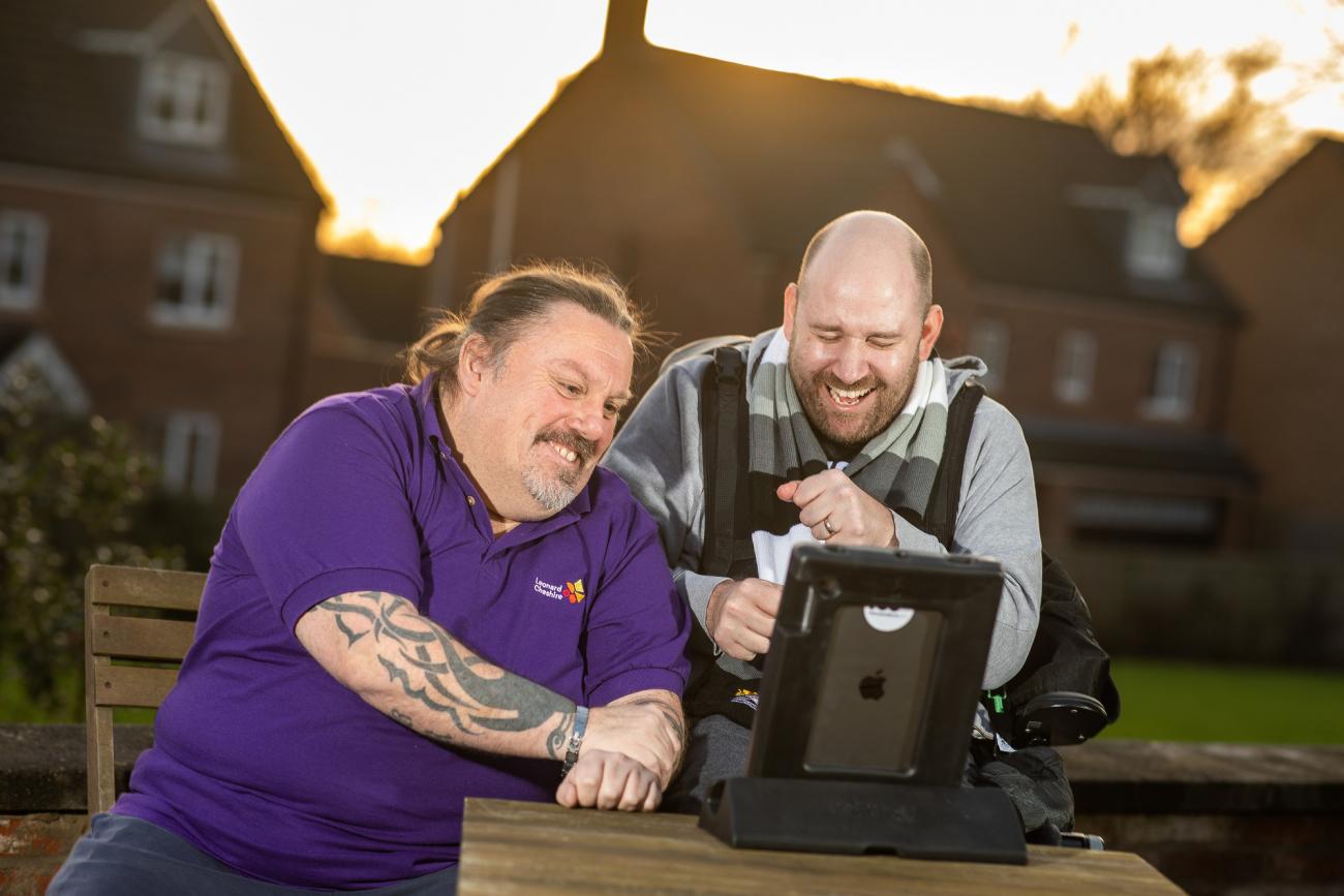 To men look at a computer screen and laugh