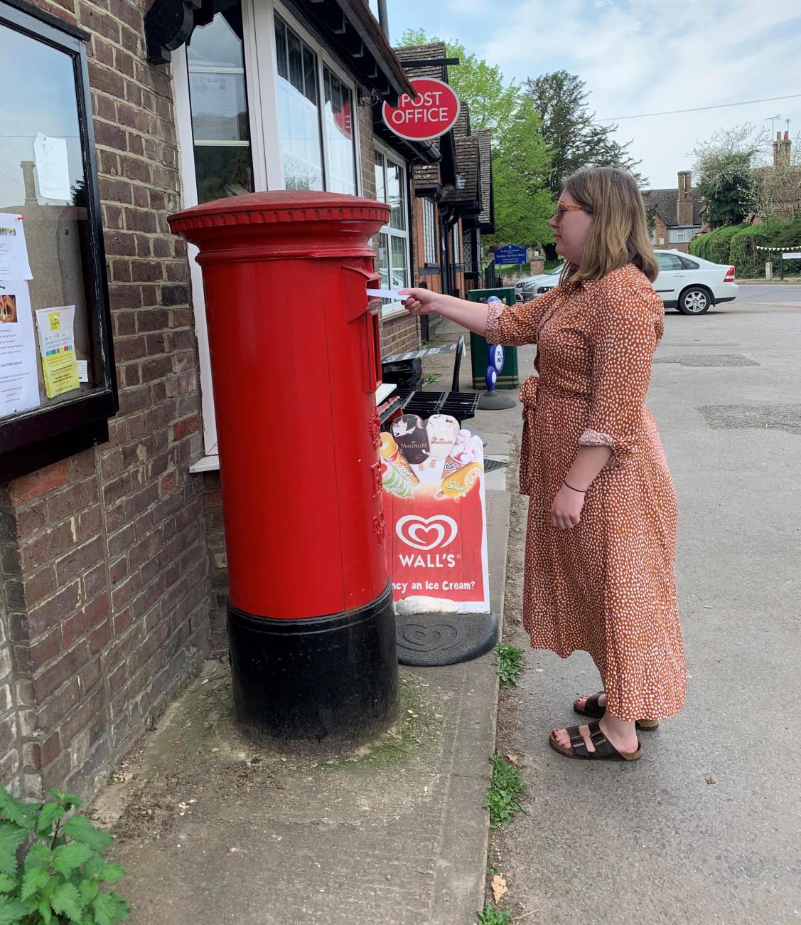 A woman posting a letter in a red letter box