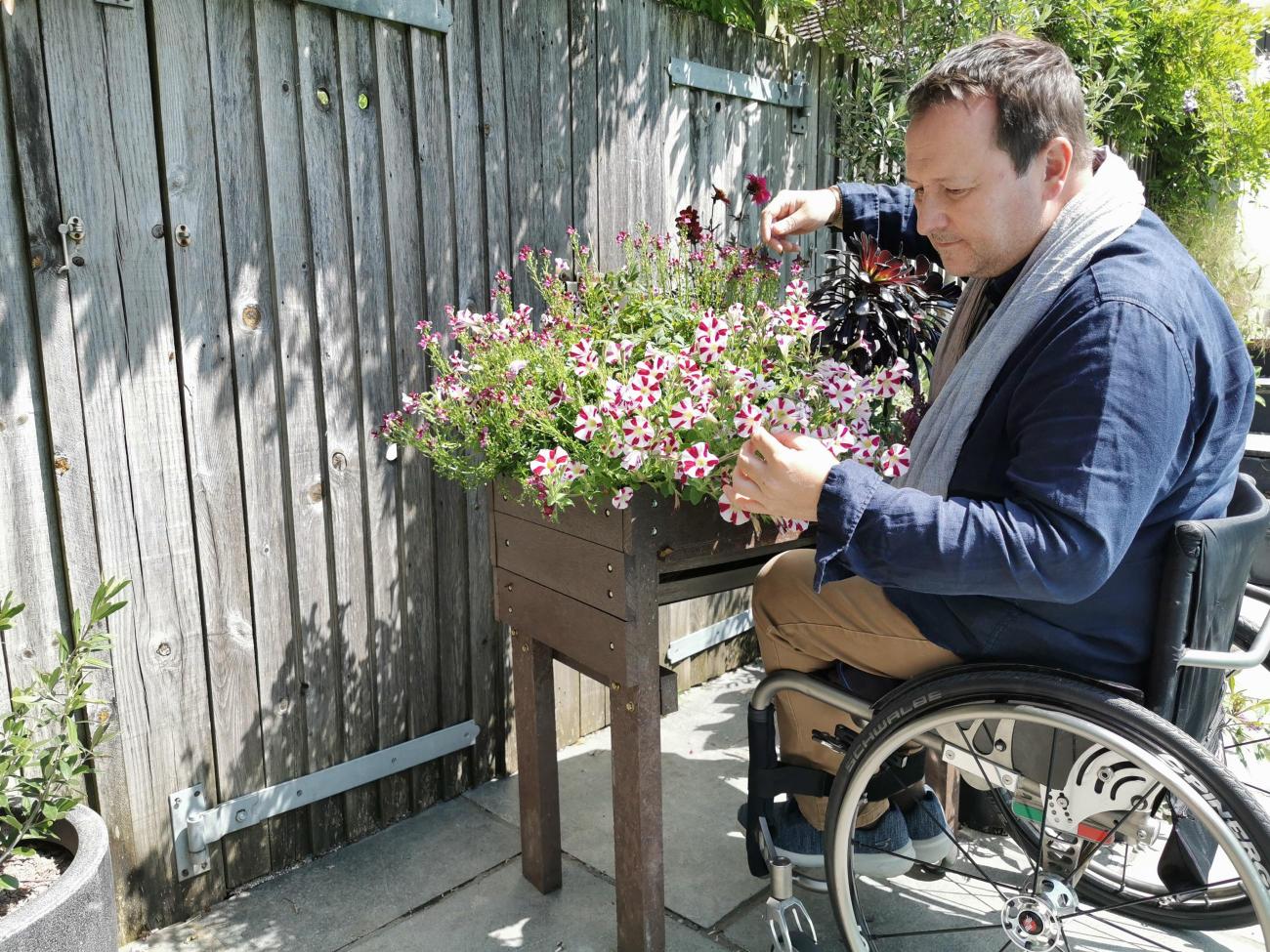 Mark Lane in his wheelchair next to a raised flower bed