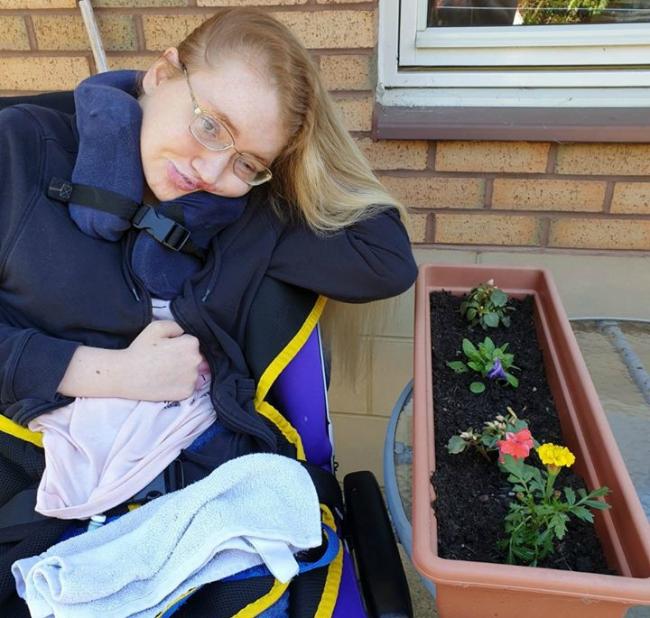 A women in a wheelchair next to a flower pot gardening