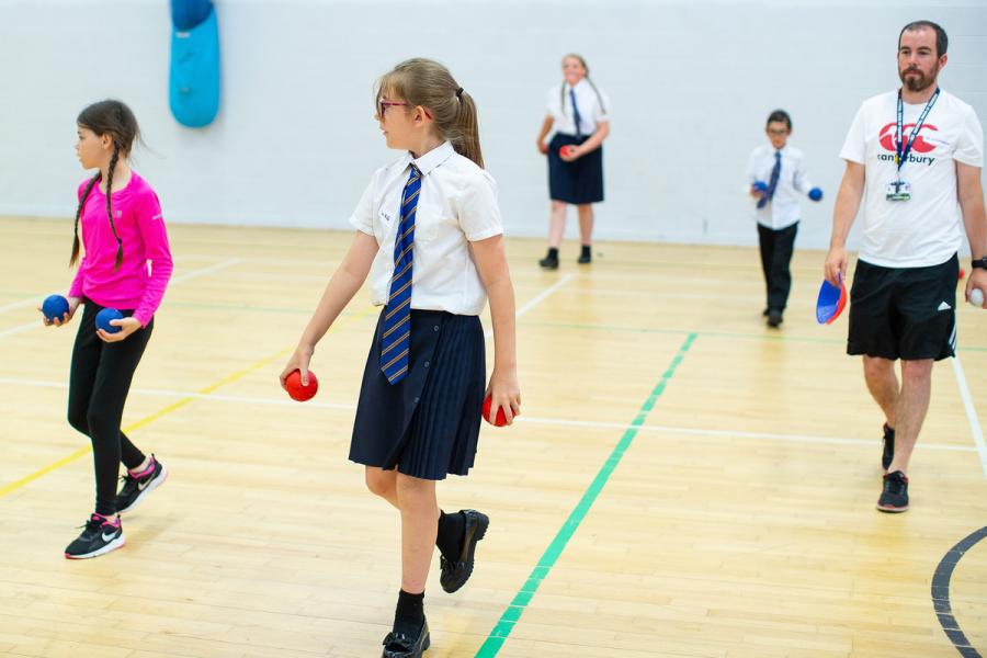 Can Doers sport A group of children in school uniform in a sports hall