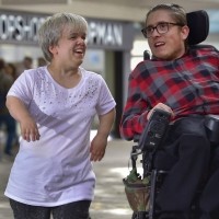 Josh and a friend talk while walking along a high street