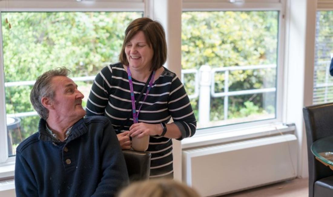 A man sitting down looking at the woman smiling behind him