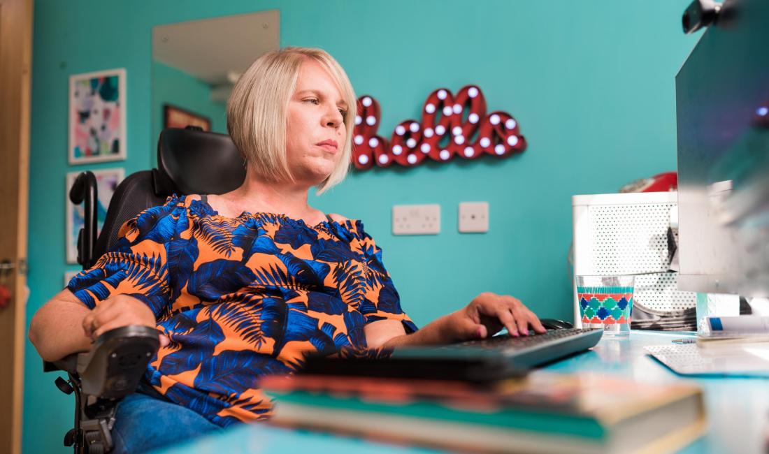 Chloe in her wheelchair typing on a keyboard at home